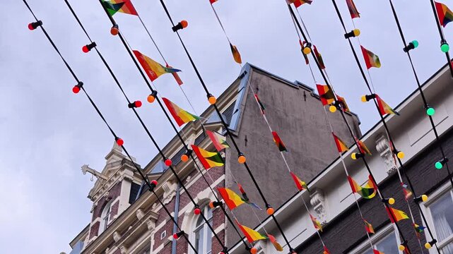 Row of pride rainbow bunting flags strung across buildings in Amsterdam