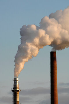 Aus dem Kamin einer Industrieanlage str&ouml;men Abgase, Rauch und Dampf