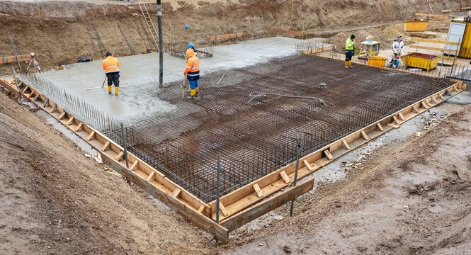 Bauarbeiter betonieren auf Baustahl ein Fundament f&uuml;r ein neues Wohnhaus