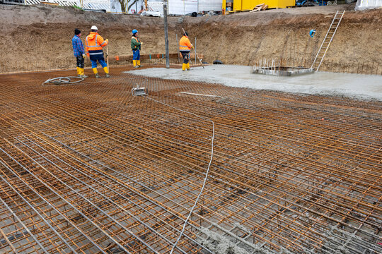 Bauarbeiter betonieren auf Baustahl ein Fundament f&uuml;r ein neues Wohnhaus