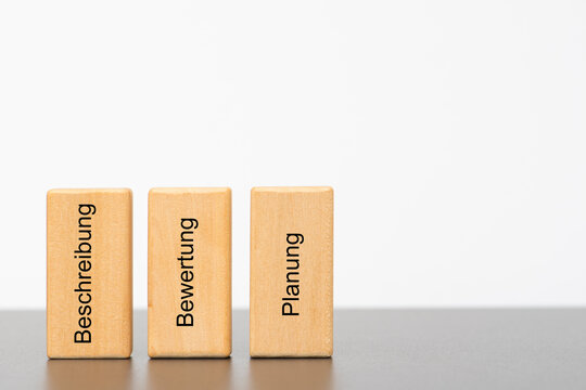 Die drei S&auml;ulen der Betriebswirtschaft, Beschreibung, Bewertung und Planung, sind auf drei Holzw&uuml;rfel gedruckt