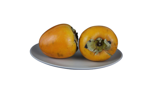 Two whole ripe orange persimmons served on a plain gray plate with ripe persimmon orange fruit sweet fruit seasonal fruit autumn fruit raw food orange color vitamin c organic food vegan diet