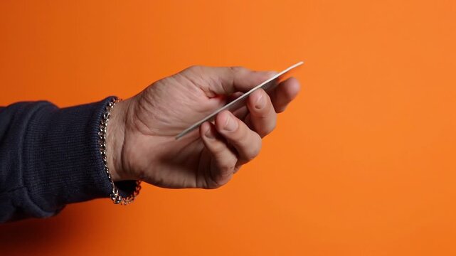 Hand holding green screen credit card over orange background business finance advertising placeholder for copy space showing mockup screen and card element.