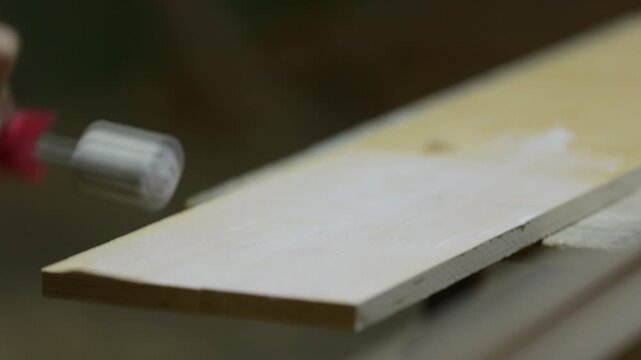 Worker spreading glue over plywood sheet with small roller