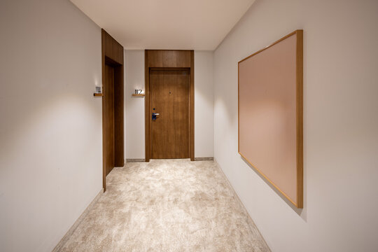 Clean hotel hallway corner with wooden room doors and frame