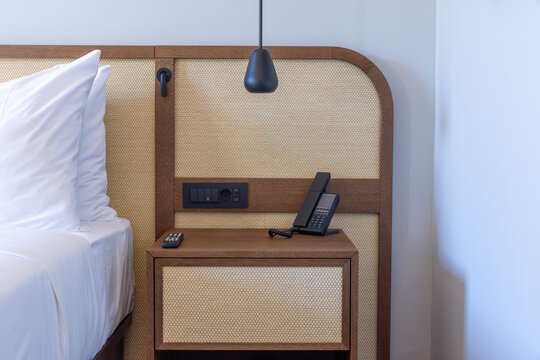 Modern hotel bedroom nightstand with rattan headboard and phone