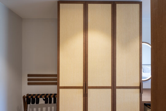 Custom wooden wardrobe with woven rattan doors in modern hotel room