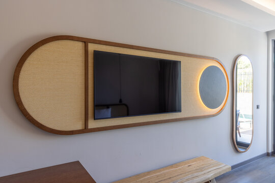 Stylish television mounted on custom wooden and rattan wall panel