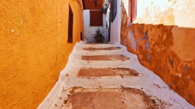 Narrow stepped alley in Anafiotika with colorful plaster walls, shutters and afternoon sun in Athens, Greece