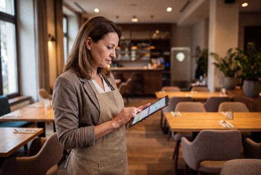 Restaurant manager checking online orders on tablet