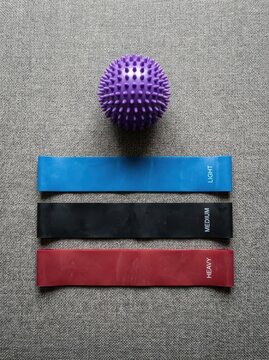 Set of Resistance Bands in Different Strengths and a Purple Massage Ball for Fitness, Yoga, and Physical Therapy
