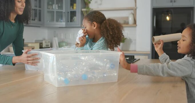African American mom with two girls moving bin sorting bottles on kitchen island adding PAPER bin