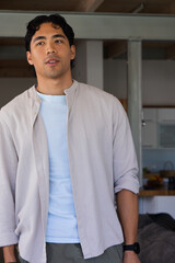 Obraz premium African American man standing in open-plan home, looking up left, wearing beige shirt, black watch