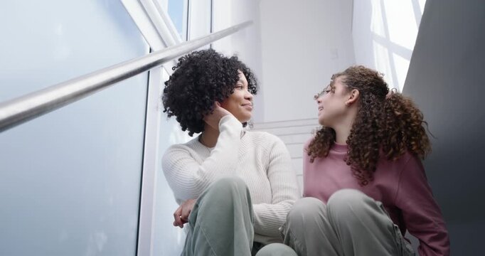 Female friends sitting on stairs, one descending handrail with smartwatch and joining