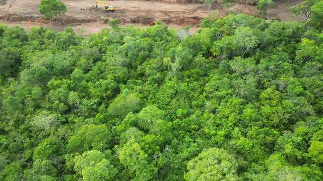 Aerial drone flyover documenting native rainforest being deforested with the use of an excavator in the Brazilian Amazon