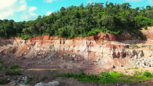 Aerial drone flyover of an open-pit aggregate mining site in the Brazilian Amazon. The footage captures the mining operation, excavation areas, heavy machinery, exposed earth, and the surrounding rain