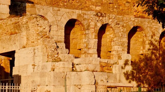 Odeon of Herodes Atticus stone arches in golden light in Athens, Greece