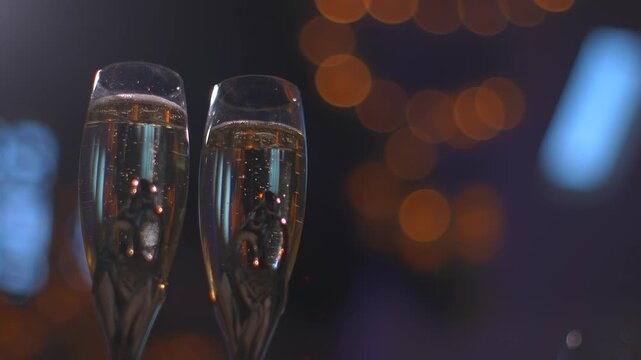 Close up of champagne glasses with bubbles and bokeh lights in the background