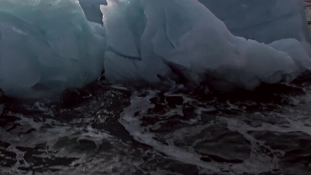 Blue ice and irregular frozen texture fill a close natural view. Additional visible detail includes dark water and surface wake, with natural light defining the surrounding forms.