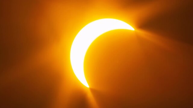 A glowing partial solar eclipse forming a sharp crescent shape, radiating intense orange light rays against a dark, contrasting background