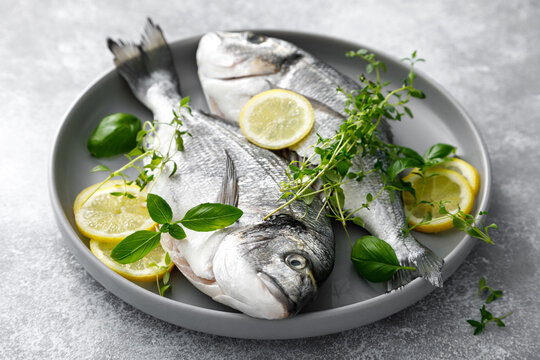 Fish raw dorado sea bream with lemon slices and herbs