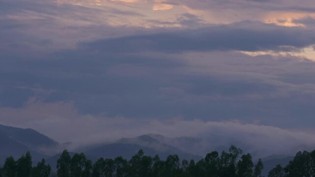 Cinematic landscape time lapse of a sea of fog flowing smoothly between complex mountain ridges during golden hour until nightfall. Beautiful nature in motion.