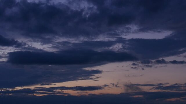 Beautiful day-to-night timelapse footage of a dramatic evening sky. Deep blue clouds move across a golden sunset sky before transitioning into dark twilight and nightfall.