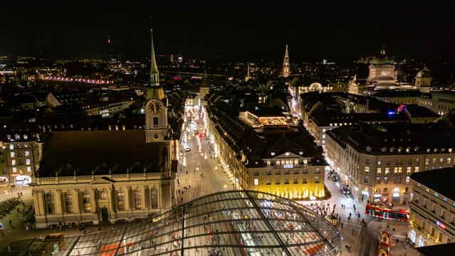 Aerial drone view over modern glass canopy at Bahnhofplatz and Spitalgasse festive street lights in Bern, Switzerland