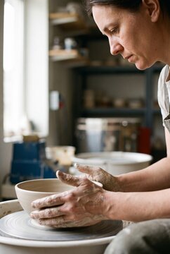 Woman Potter Shaping Clay At Wheel In Profile