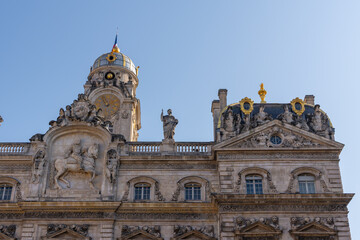 Fototapeta premium Ornate historic building facade with a clock tower and golden dome under blue sky. Lyon