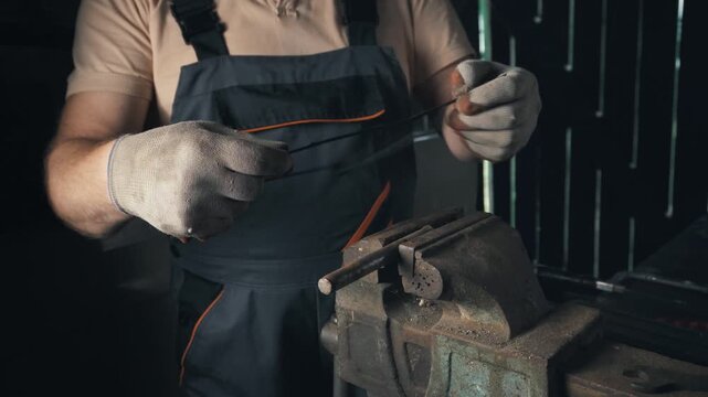 Male technician in gray overalls uses tools to manipulate metal components in a workshop, showcasing a series of actions with a vice and various tools in a well-lit industrial setting