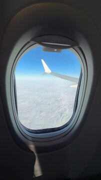 Three airplane windows show views of expansive white clouds below the aircraft window frames are visible surrounding the view through the airplane window structure