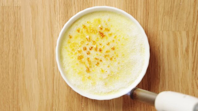 Kitchen torch caramelizes sugar on crema catalana. High heat creates glassy crust over chilled citrus custard. Traditional Catalan dessert brings crisp topping and creamy center to restaurant menu.