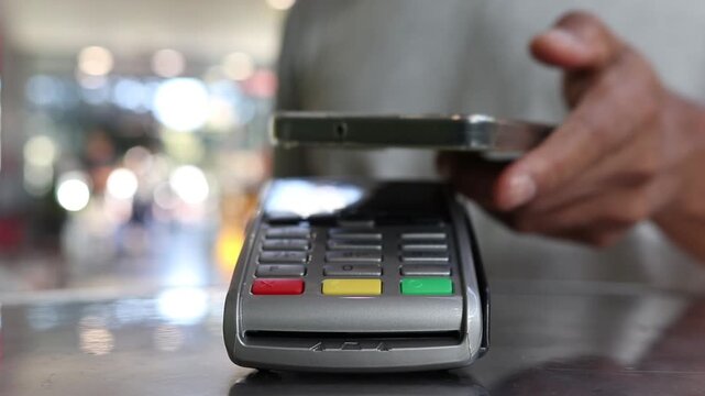 Customer using smartphone for contactless payment on a pos terminal in a store, showcasing secure nfc digital transaction technology