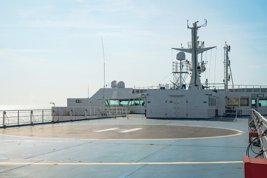 A helipad on the upper deck of a large vessel at sea. The image shows the landing zone, ship's bridge, and communication equipment, representing maritime safety, logistics, and modern transport.