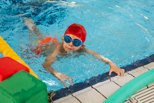 Child learning swimming lessons wearing goggles and cap