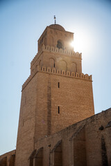 Obraz premium Sun behind a minaret on the Great Mosque of Kairouan in the medina, in Kairouan, Tunisia