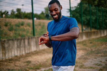 Fototapeta premium African American man checking fitness tracker during outdoor workout