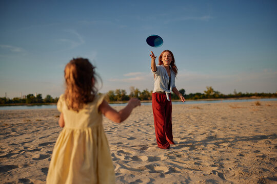 Mother and daughter playing frisbee on beach