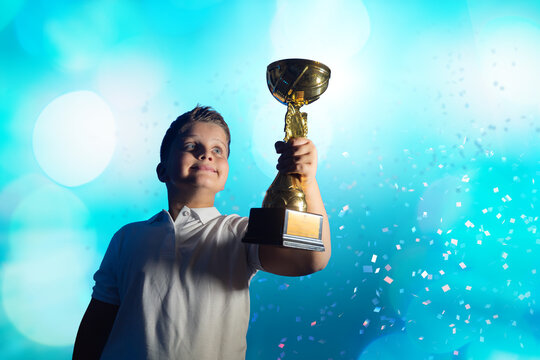 Boy Celebrating with Golden Trophy  cup  and Confetti on Blue Background