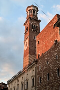Medieval Torre dei Lamberti clock tower illuminated at sunset in Verona Italy