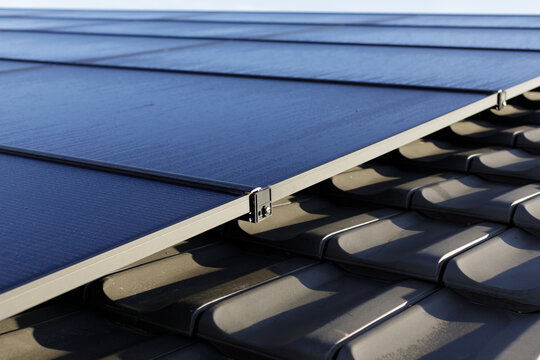 close-up shot of photovoltaic panels next to roof tiles in the morning dew