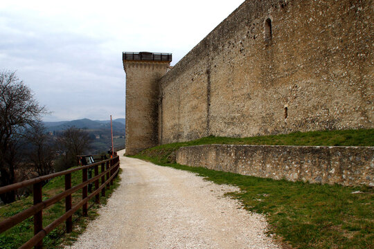 SPOLETO, ITALY - FEBRUARY 7, 2017: Rocca Albornoziana. A gravel walking path running alongside the historic stone walls of the fortress, used to stroll around and enjoy views of the surrounding hills