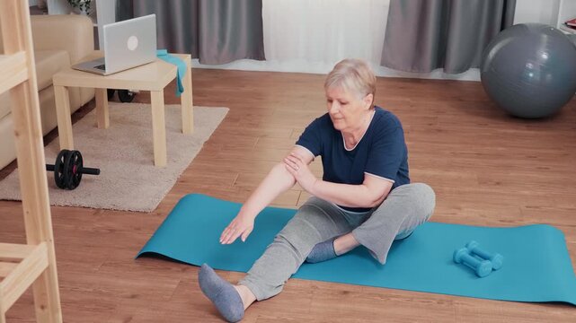Senior woman stretches toward her extended leg on a yoga mat, supporting flexibility, mobility and independent home fitness during an active aging routine, with a focus on healthy aging.