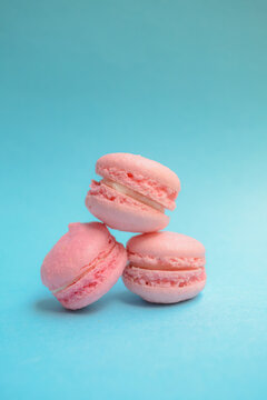 Stacked pink French macarons on a teal blue background