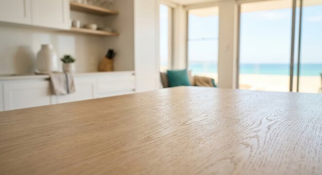 Empty wooden table top with blurred modern kitchen and beach view background. Ideal for product mockup, food presentation, and coastal lifestyle concepts. Bright and airy atmosphere.