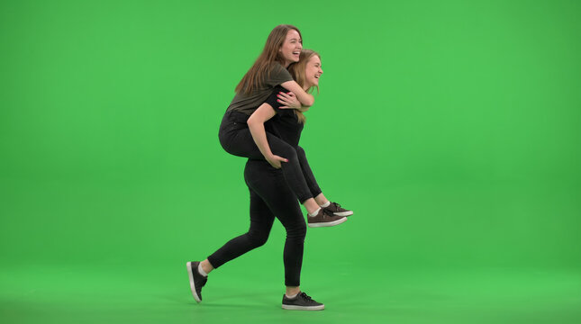 Woman Carrying Friend on Her Back Against Green Background