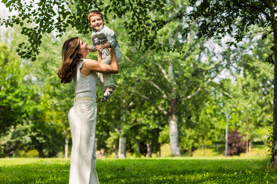 Mother lifting son high in air bonding outdoors