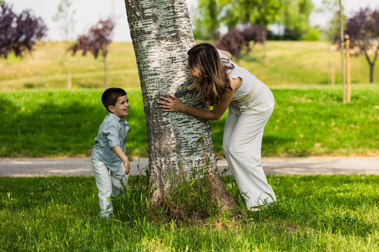 Mother and son playing hide and seek in park