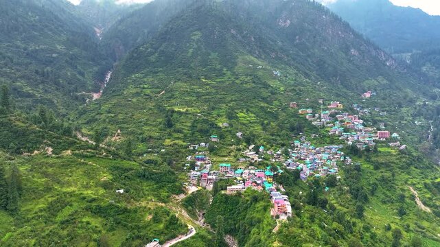 Drone pullback reveal of the beautiful summer destination of Tosh nestled deep within the massive V-shaped gorge of Parvati Valley, India.